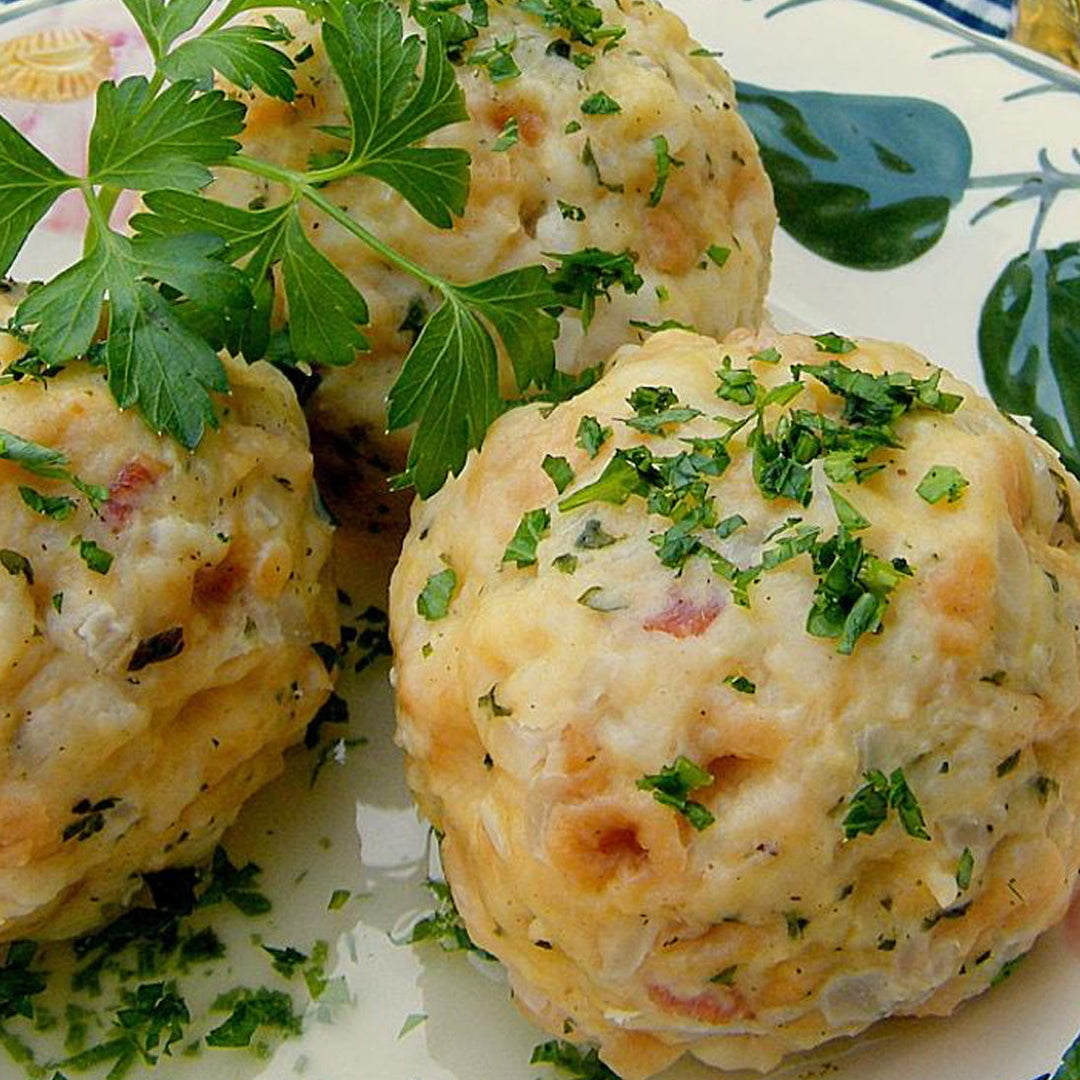 Bread dumplings topped with chopped parsley on a patterned plate
