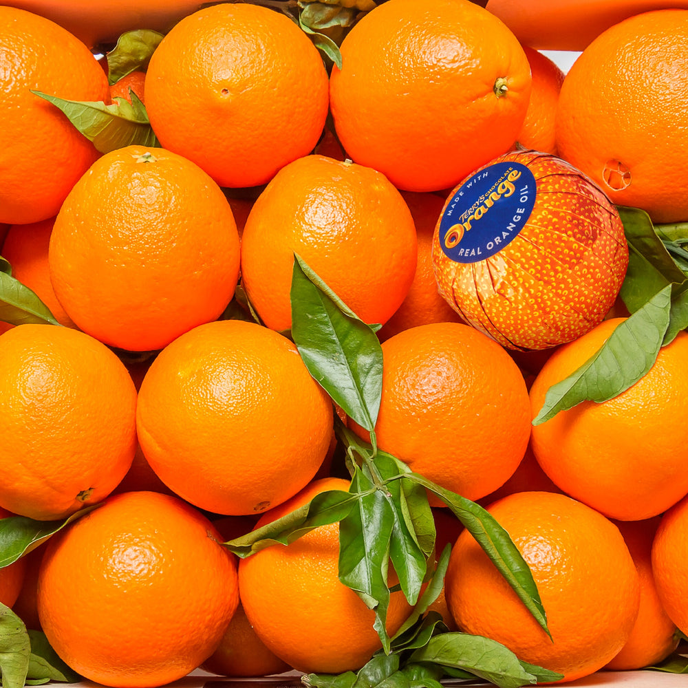 Foil-wrapped Terry's Chocolate Orange displayed among fresh oranges