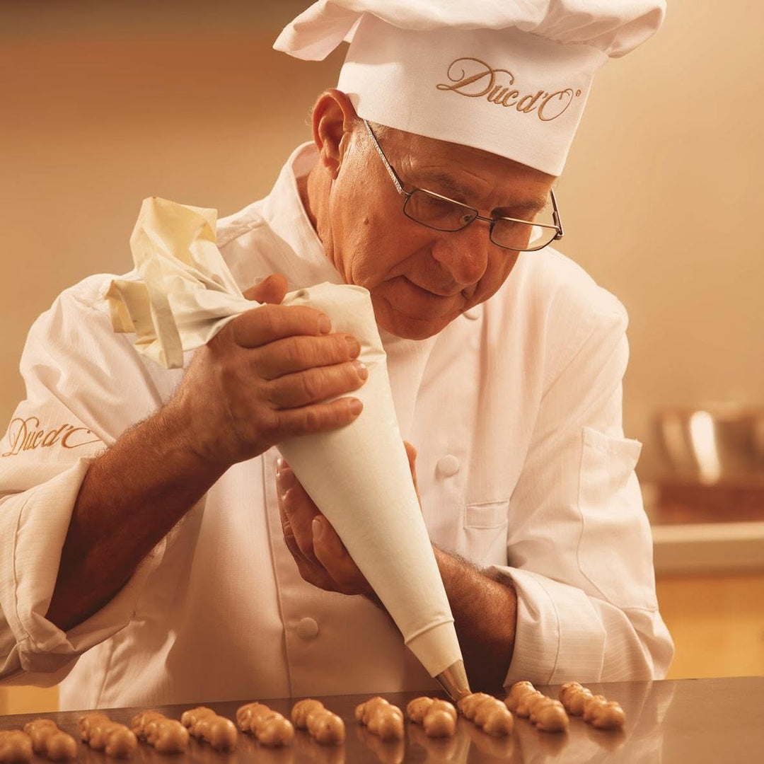 Duc d’O chocolatier piping truffle filling in a kitchen