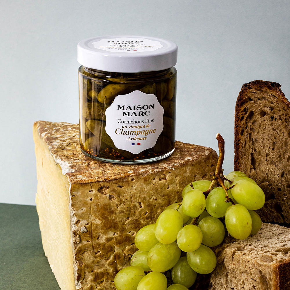 Maison Marc cornichons with Champagne vinegar jar beside bread and grapes