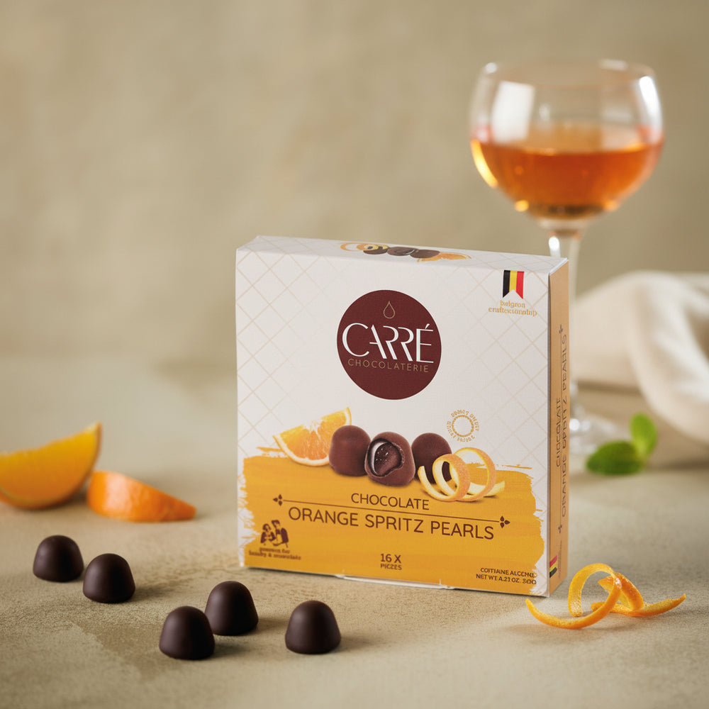 Box of Carre Chocolate Orange Spritz Pearls with chocolate pearls on a beige surface.