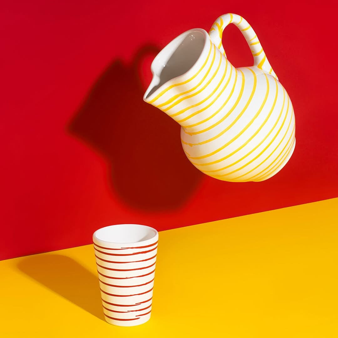 Red flamed handleless drinking mug with a yellow striped jug; jug sold separately