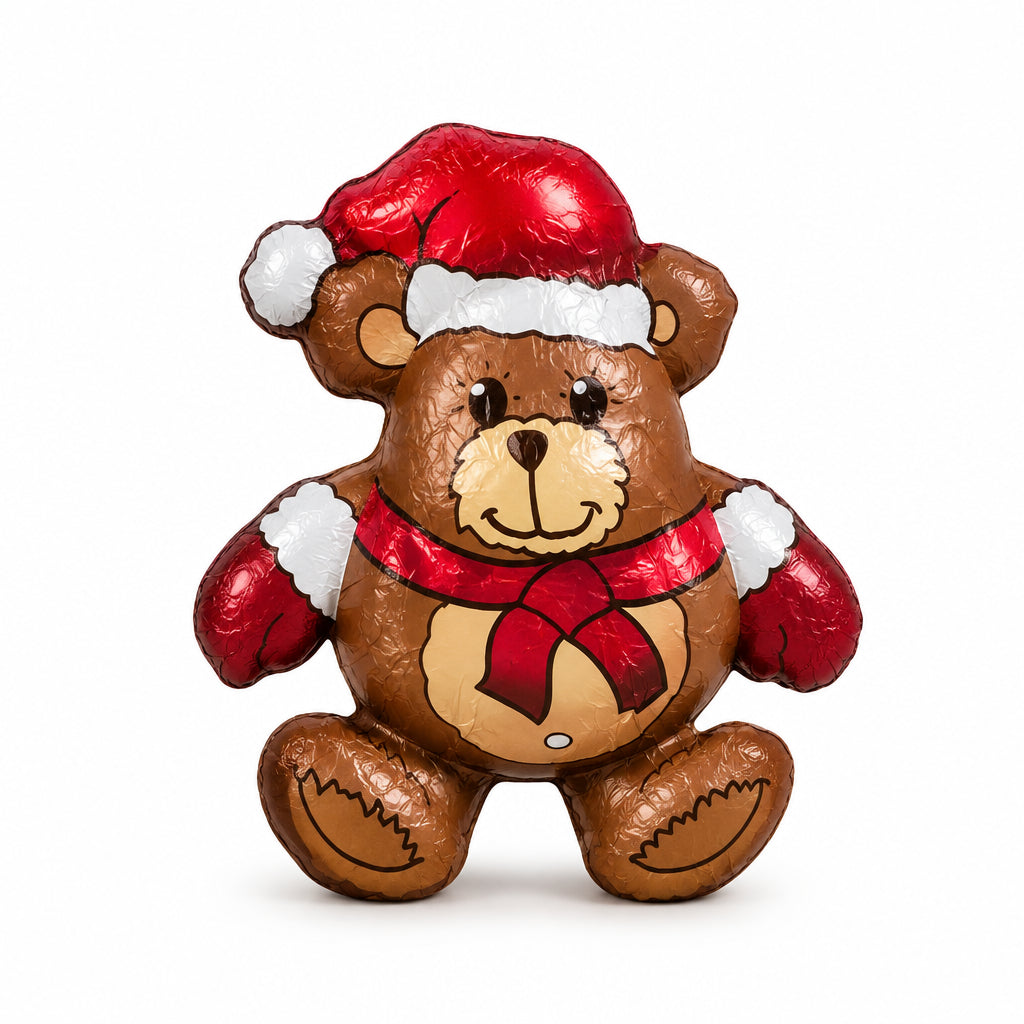 A foil-wrapped Christmas teddy bear decoration or candy, wearing a red Santa hat with white trim and a red bow tie, set against a plain white background.