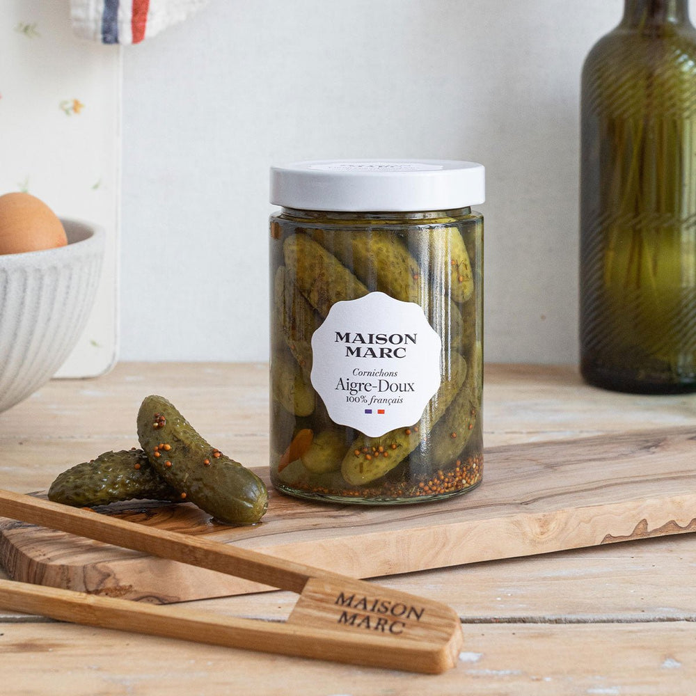 Maison Marc Cornichons Aigre-Doux 310 g jar with cornichons on a wooden board